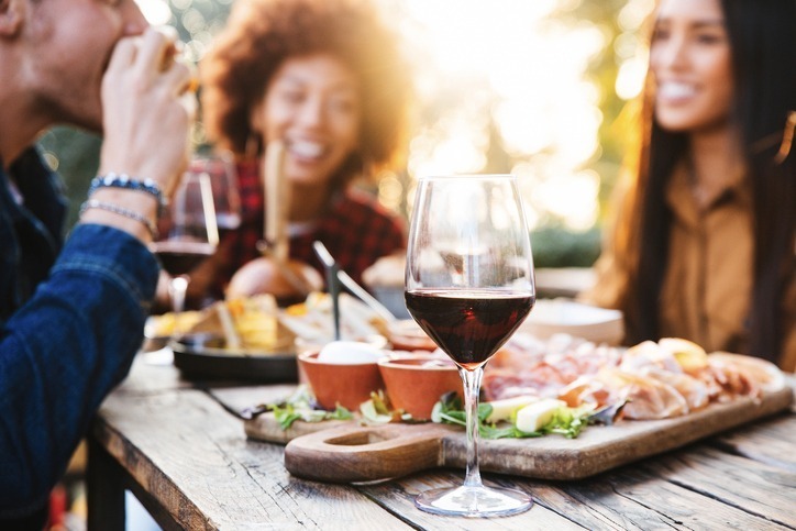 Image of friends eating appetizers and drinking wine.