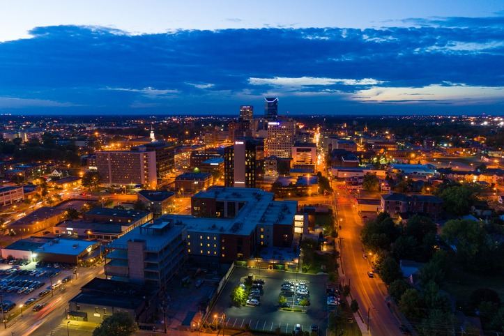 Downtown Lexington aerial view at dusk with illuminated streets and a partly cloudy sky.